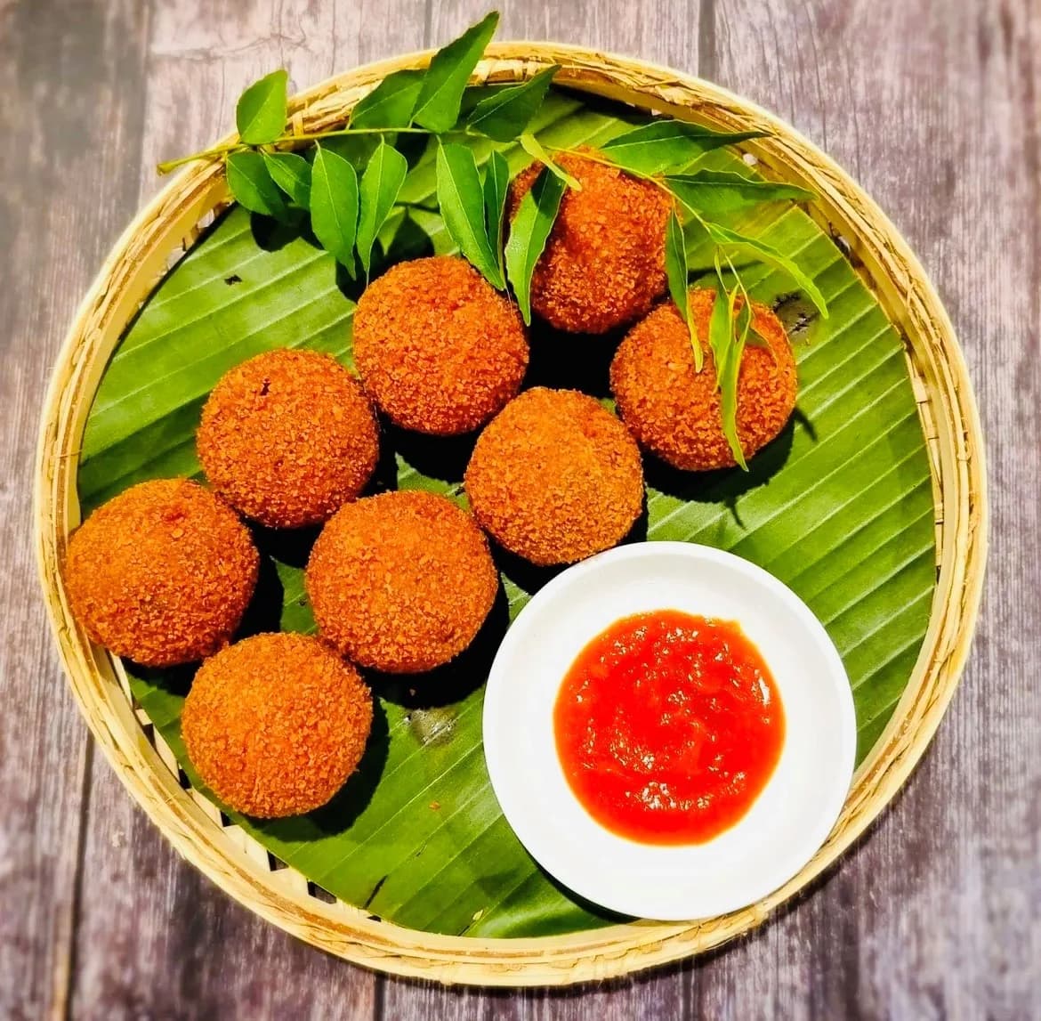 Golden crispy Sri Lankan fish cutlet balls in a woven basket with sweet chili dipping sauce