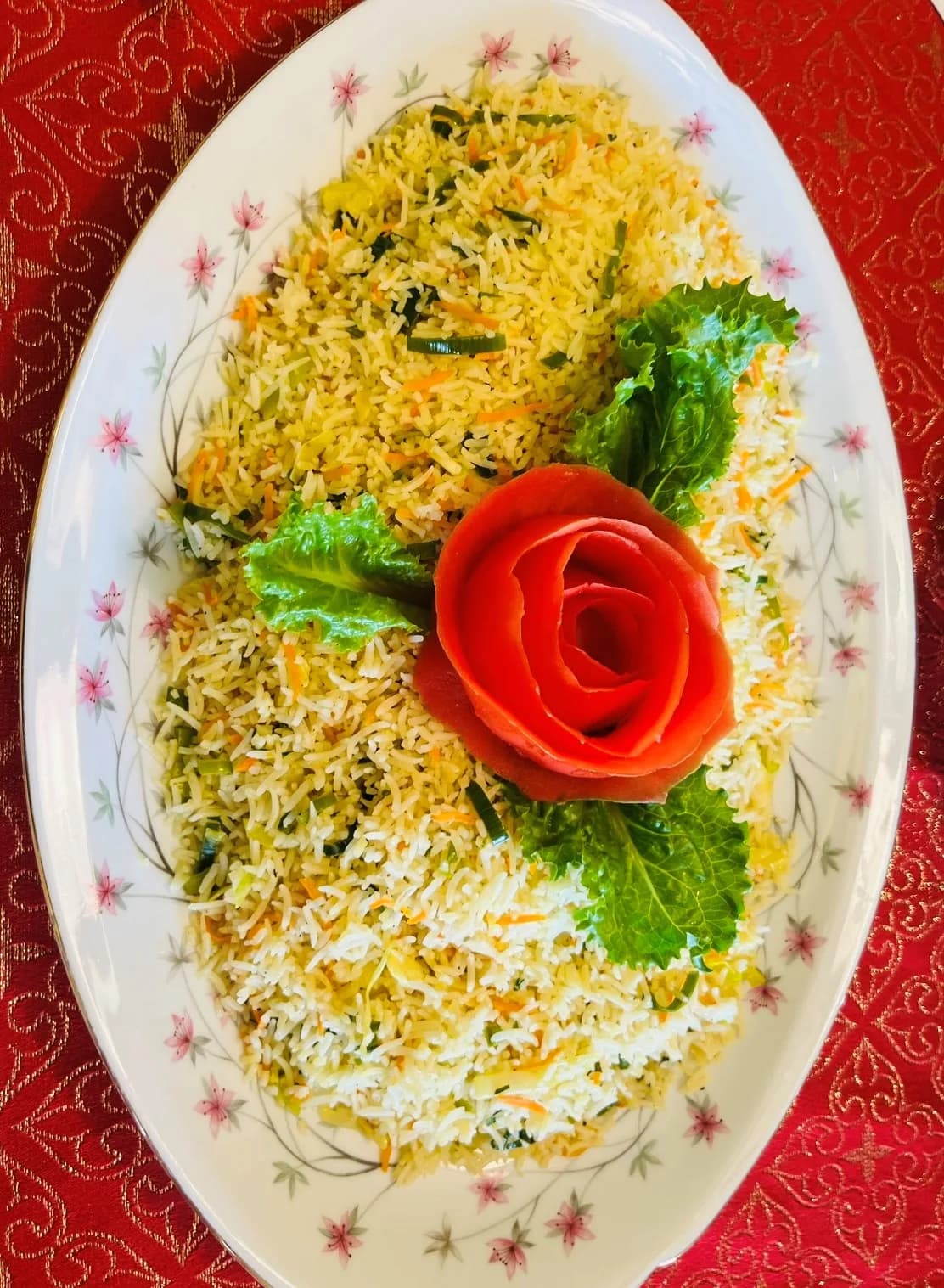 Beautifully plated saffron yellow rice with tomato rose garnish