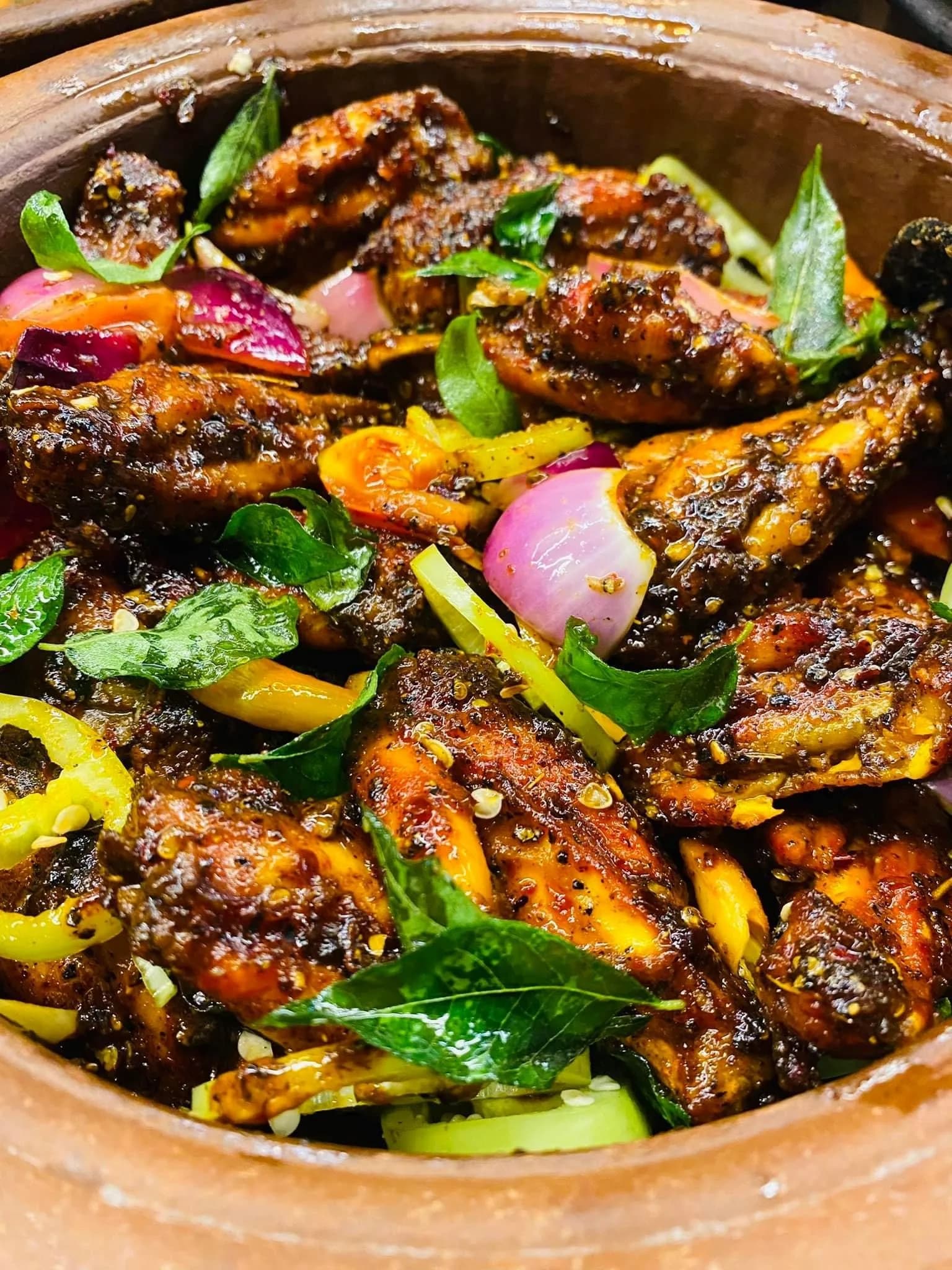 Spicy Sri Lankan clay pot chicken curry with curry leaves and peppers