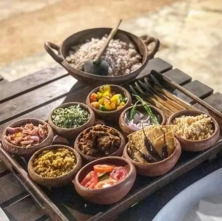 Traditional Sri Lankan rice and curry spread in clay pots on wooden tray by Chef Kal