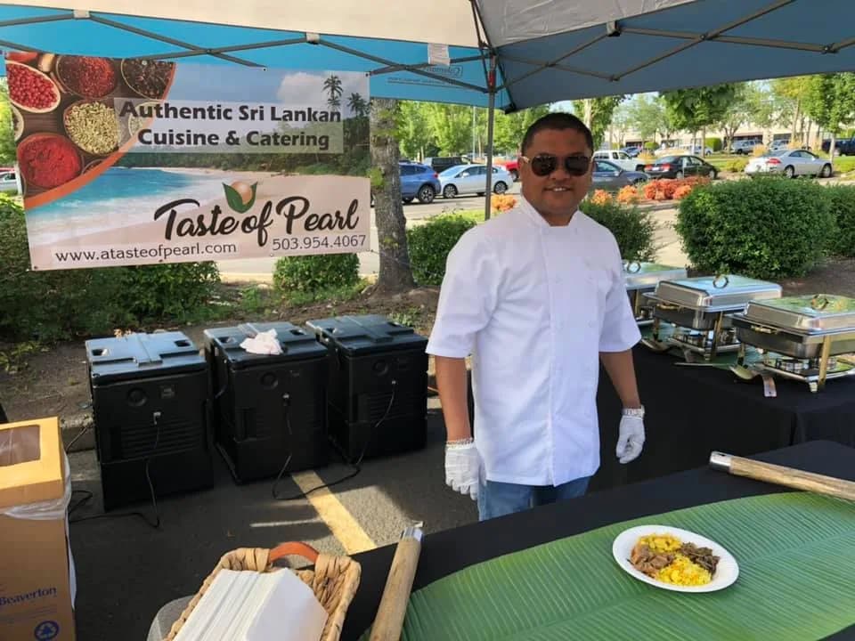Chef Kal Peiris at the Taste of Pearl farmers market booth with banner and food display